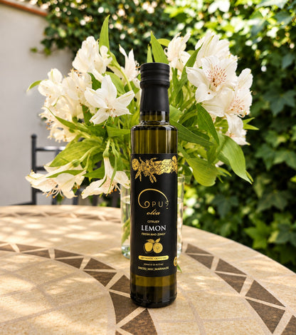 A bottle of Opus Lemon olive oil with white flowers in the background.
